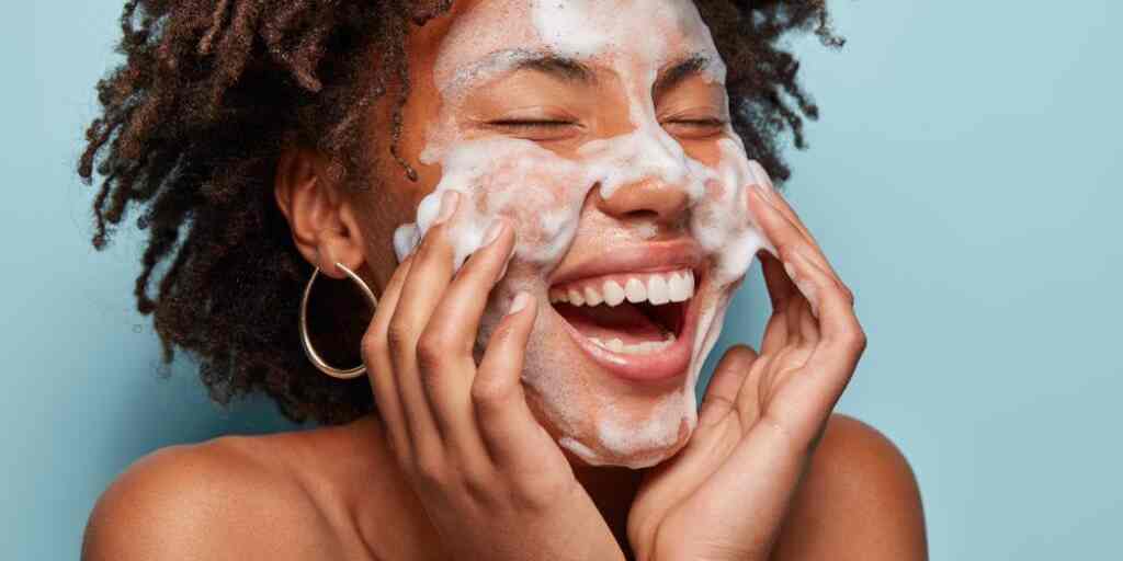 Cheerful,Black,Female,Model,Applies,Foaming,Cleanser,,Has,Clean,Fresh Smiling woman applying a gently foaming facial cleaner